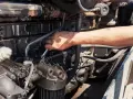 Mano con chiave inglese lavora su un motore sporco d'olio, forse per riparare cos'è l'alternatore.