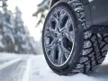 Pneumatici invernali per auto elettriche su strada innevata, con cerchio in lega e battistrada coperto di neve.