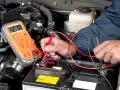 Controllo del voltaggio della batteria auto con multimetro. Il display segna 12.78V.