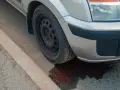 Un'auto perde liquido rosso da ferma, formando una pozza sull'asfalto vicino al marciapiede.