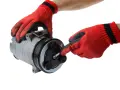 Mani guantate rosse lavorano su un compressore per la sostituzione del compressore aria condizionata auto.