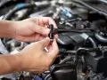 Mani che tengono un iniettore auto, componente essenziale per il funzionamento del motore.