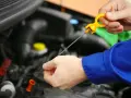 Controllo livello olio motore. La mano estrae l'astina per verificare la presenza di perdita olio motore.