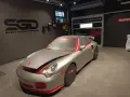Auto sportiva pronta per la verniciatura, con protezioni rosse e cellophane. Il logo "SGD Sport Garage Detailing" è visibile.