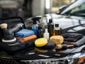 Kit per la carteggiatura auto: lucidatrice, tamponi, spazzole, panni in microfibra e flaconi di prodotti per la cura dell'auto.