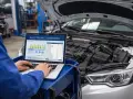 Meccanico esegue diagnosi centralina auto con laptop. Il computer mostra grafici e dati tecnici.