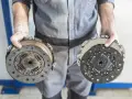 Meccanico mostra due dischi frizione, essenziali per capire a cosa serve la frizione: disconnettere il motore dalla trasmissione per cambiare marcia.