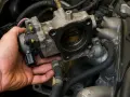 Mano che installa un corpo farfallato su un motore.
