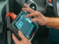 Un meccanico usa uno scanner per scoprire quanto costa una diagnosi auto.