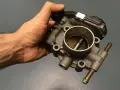 Mano che tiene una valvola a farfalla motore benzina, componente essenziale per il controllo del flusso d'aria.