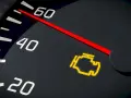 Cruscotto auto con spia motore accesa, indicatore rosso su tachimetro.