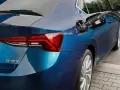 Rifornimento di un'auto blu con motore a metano. La pompa è inserita nel serbatoio.