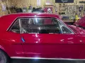 Auto d'epoca con vernice rosso candy apple lucida, in un garage con attrezzi appesi.