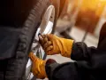 Mani guantate stringono bulloni ruota auto, seguendo la tabella coppia serraggio per sicurezza.