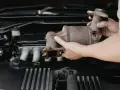 Mani che rimuovono un catalizzatore arrugginito dal vano motore di un'auto. Riparazione del fap auto.