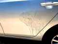 Sporco e macchie sul fianco di un'auto argentata, forse dopo un trattamento di soda blasting.