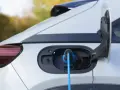 Auto elettrica in carica, con cavo blu collegato alla porta. La coppia motore è pronta per la prossima avventura.