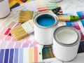 Pennelli e barattoli di vernice su campioni di colore. Una scelta di tonalità, tra cui vernice perlata o metallizzata, per il tuo prossimo progetto.