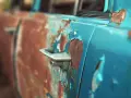 Portiera di un'auto blu con vernice scrostata e ruggine evidente. Un lavoro di restauro per togliere la ruggine sarebbe necessario per riportarla al suo antico splendore.