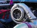 Dettaglio di un motore con un turbo benzina cromato, cavi rossi e un tappo dell'olio.