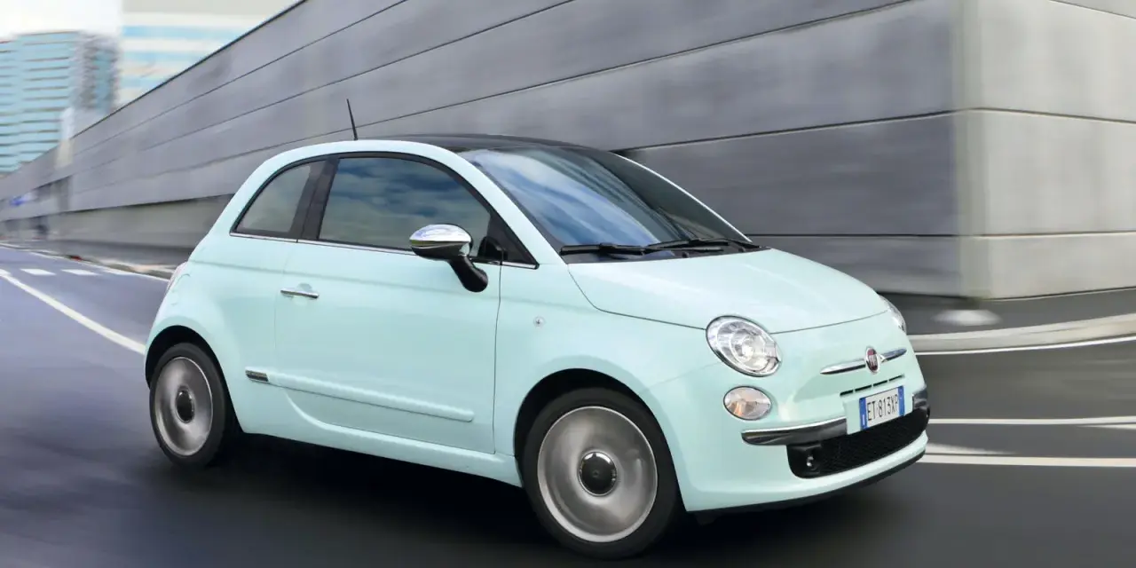 Fiat 500 azzurra in movimento, con la sua linea iconica che esprime la coppia massima di stile e agilità urbana.