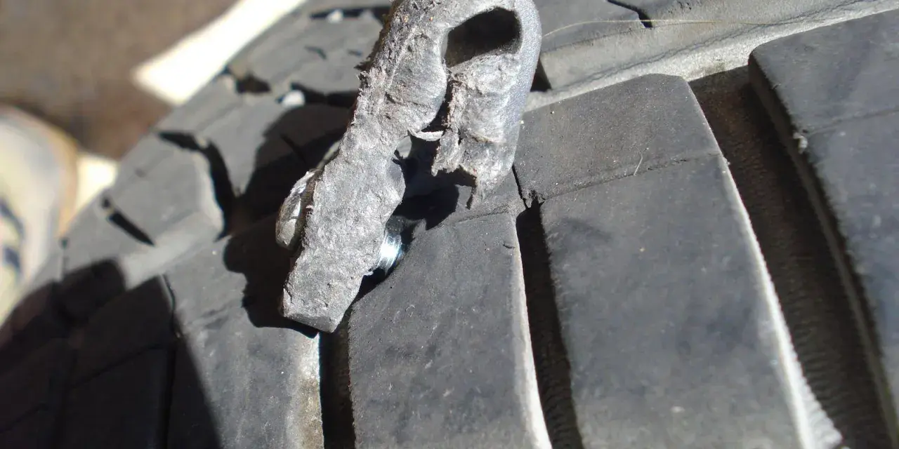 Un pezzo di gomma strappato, forse da una spalla pneumatico, è conficcato nel battistrada di un pneumatico.