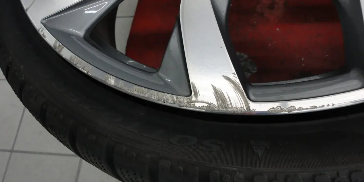Cerchio graffiato sul marciapiede, con segni evidenti di sfregamento sul bordo metallico.