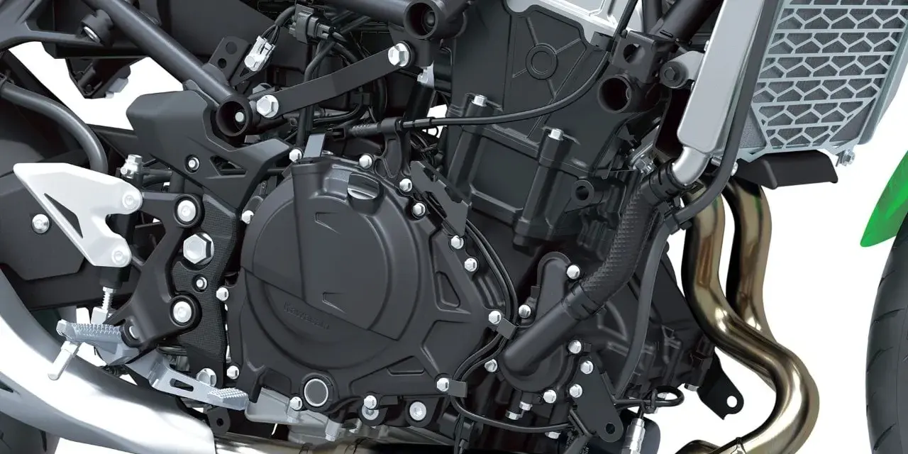 Dettaglio motore di una moto, con tubi di scarico lucidi e componenti meccanici complessi. Il freno motore è parte integrante di questo sistema.