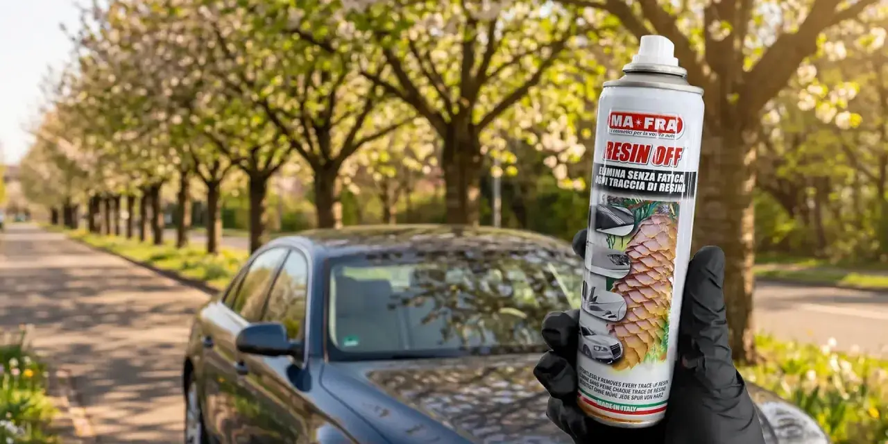 Mano guantata tiene spray MAFRA Resin Off per rimuovere resina e lucidare la plastica dell'auto, con auto scura sullo sfondo.