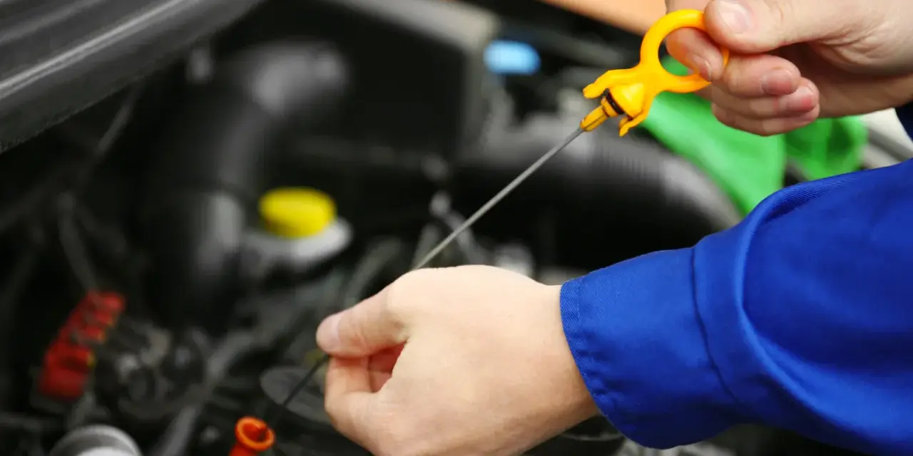 Controllo livello olio motore. La mano estrae l'astina per verificare la presenza di perdita olio motore.
