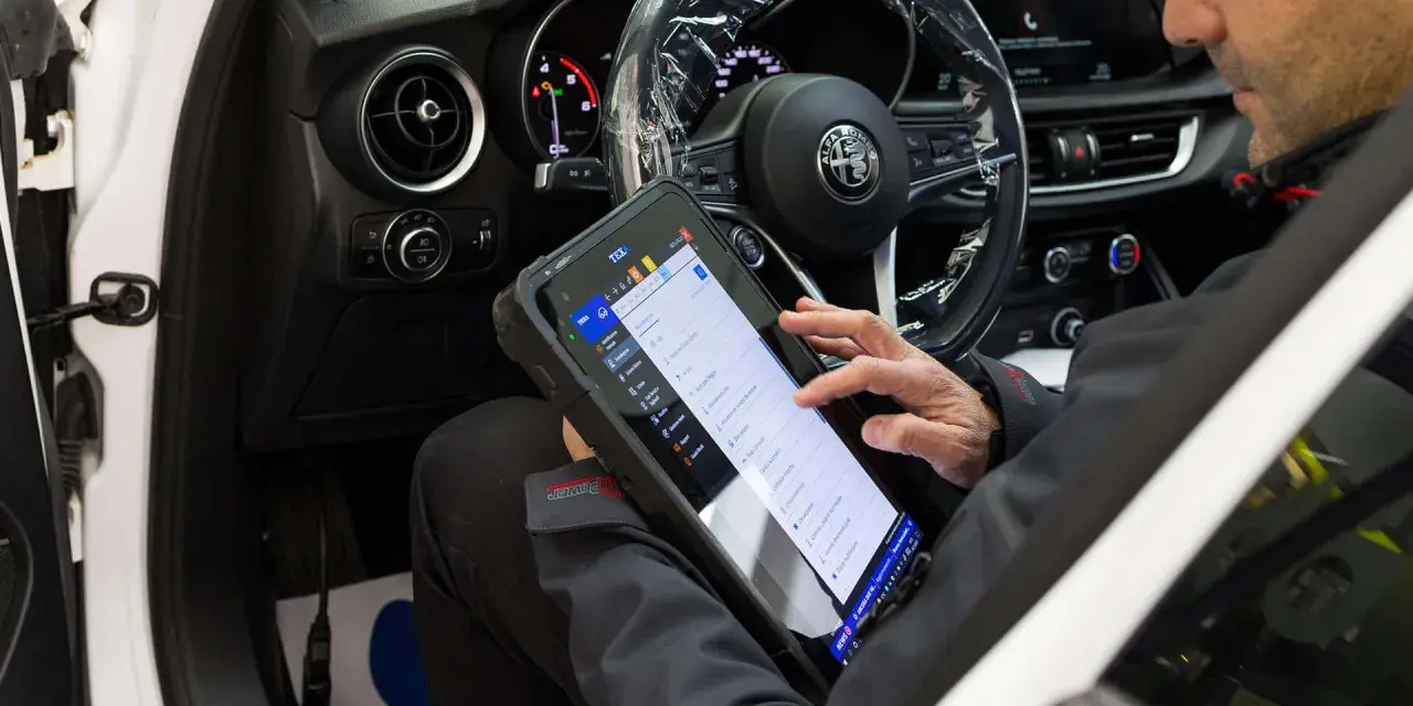 Meccanico usa tablet per diagnosticare la centralina auto. Il dispositivo mostra le opzioni di controllo e i dati del veicolo.