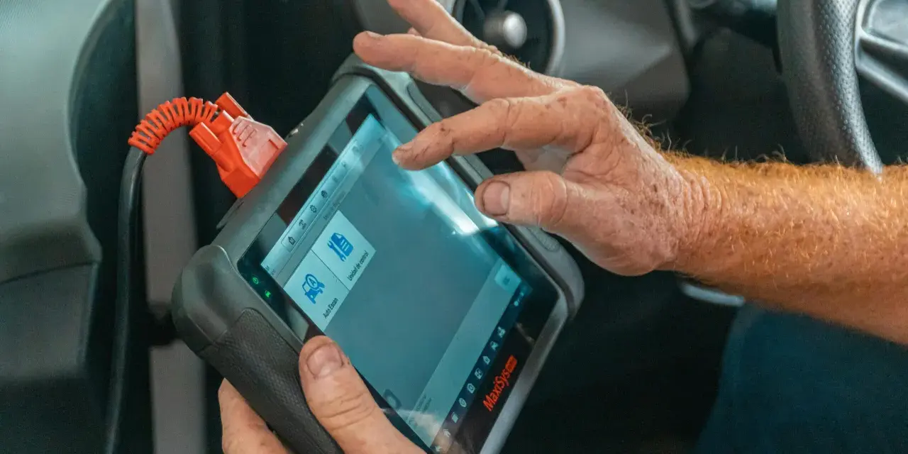 Un meccanico usa uno scanner per scoprire quanto costa una diagnosi auto.