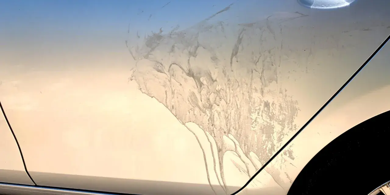 Sporco e macchie sul fianco di un'auto argentata, forse dopo un trattamento di soda blasting.