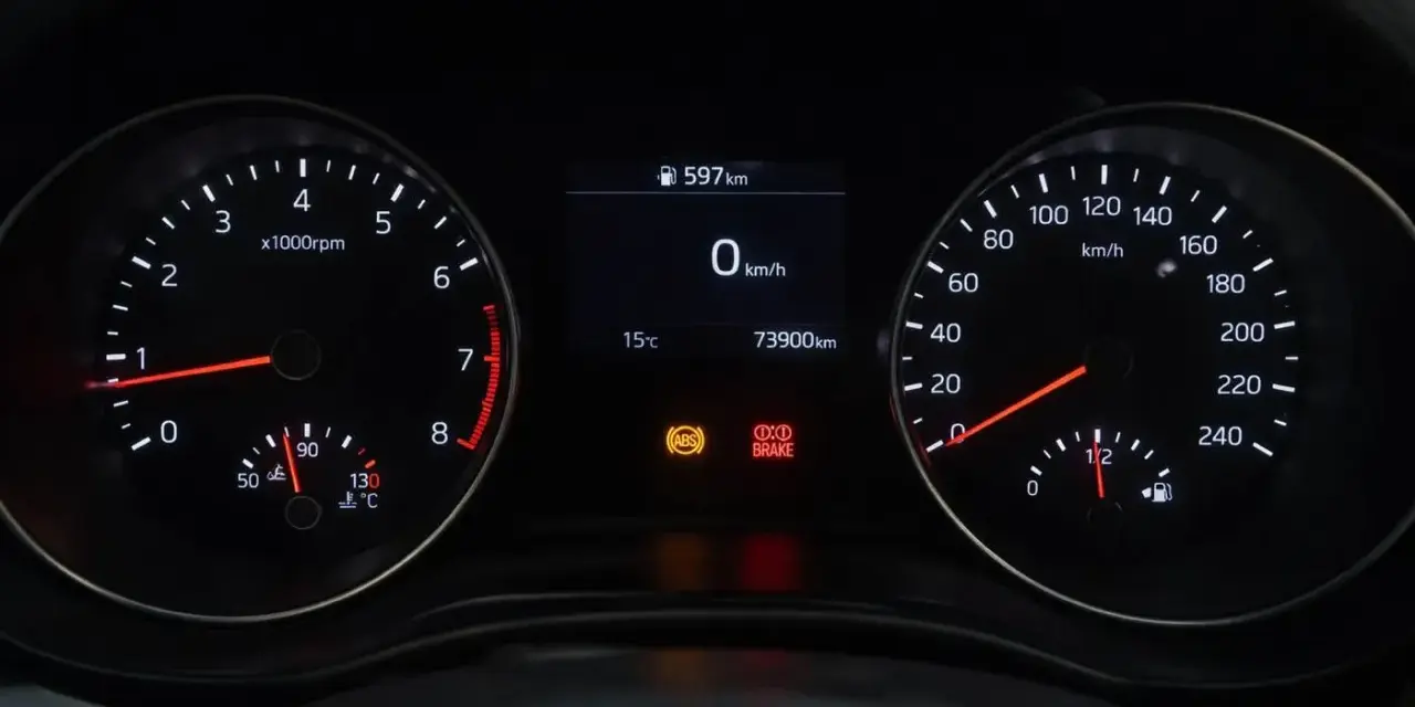Cruscotto auto con tachimetro, contagiri e spia freno a mano accesa.