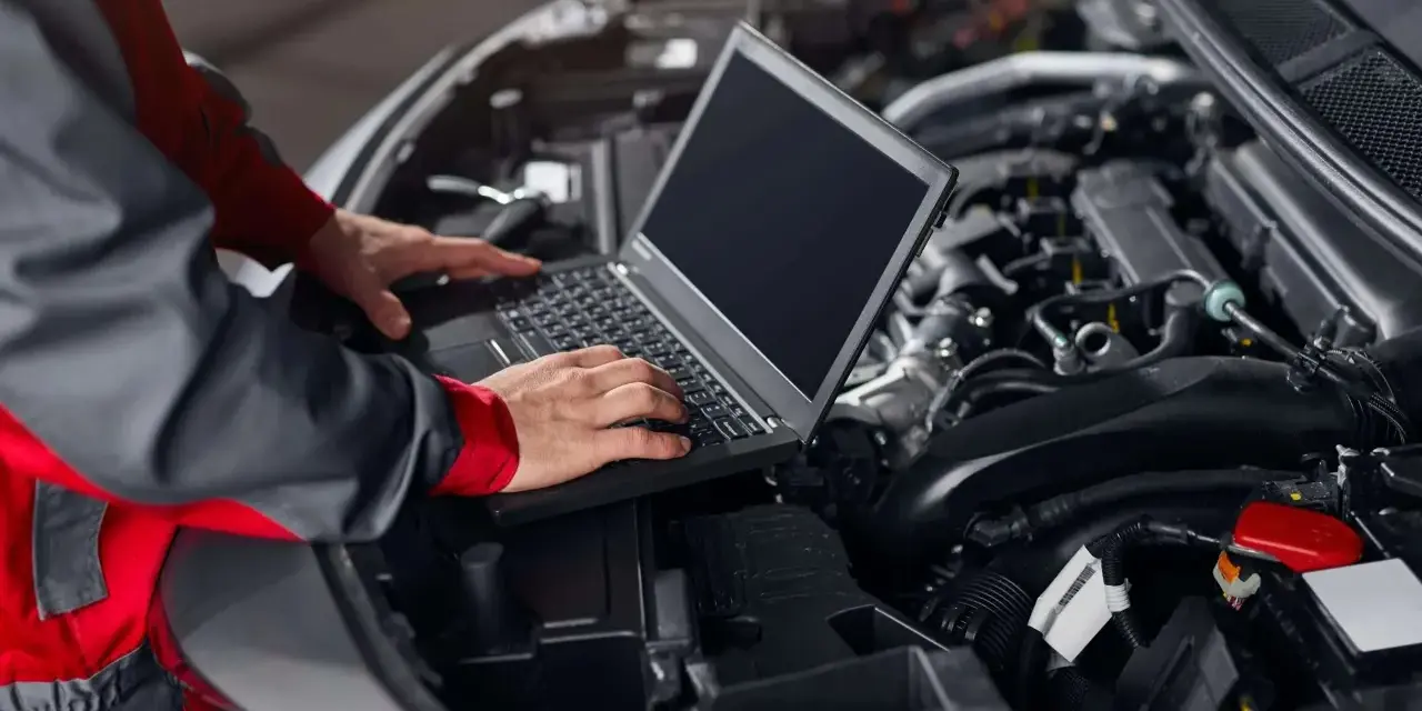 Meccanico con laptop analizza il motore per capire quante centraline ha una macchina.