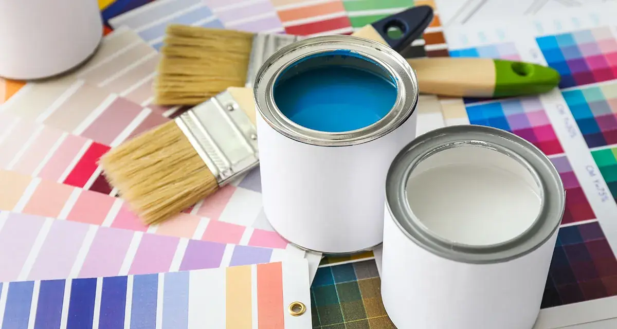 Pennelli e barattoli di vernice su campioni di colore. Una scelta di tonalità, tra cui vernice perlata o metallizzata, per il tuo prossimo progetto.