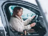 Donna al volante in un'auto coperta di neve, con le mani sul volante. Impara come guidare sulla neve in sicurezza.