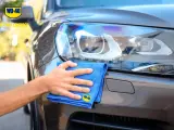 Mano che lucida fari auto con WD-40 e panno blu. Ottimo lavoro!