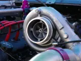 Dettaglio di un motore con un turbo benzina cromato, cavi rossi e un tappo dell'olio.