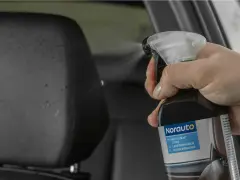 Mano spruzza detergente su sedile auto in pelle per pulire pelle.