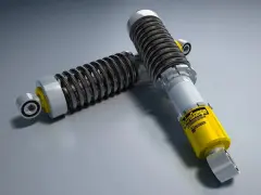 Due ammortizzatori auto di alta qualità, uno giallo con logo "ExtraDampe", pronti a migliorare le prestazioni su strada.