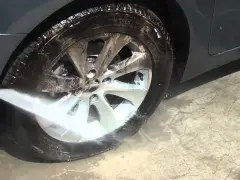 Un getto d'acqua ad alta pressione pulisce un cerchio in lega, mostrando come pulire i cerchi in lega in modo efficace.