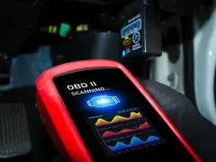 Scanner OBD II in uso per analizzare l'ECU dell'auto, mostrando grafici di sistema.