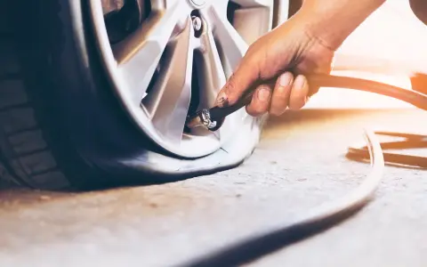 Mano che gonfia una gomma di un SUV, controllando la pressione gomme suv per un viaggio sicuro.