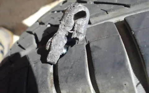 Un pezzo di gomma strappato, forse da una spalla pneumatico, è conficcato nel battistrada di un pneumatico.