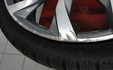 Cerchio graffiato sul marciapiede, con segni evidenti di sfregamento sul bordo metallico.