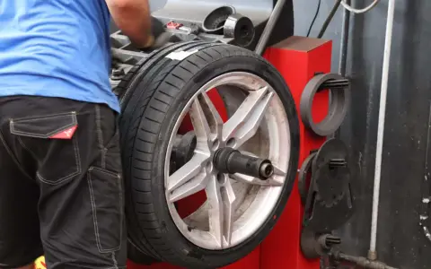 Meccanico effettua la bilanciatura gomme su un'auto sportiva. L'operazione garantisce una guida fluida e sicura.