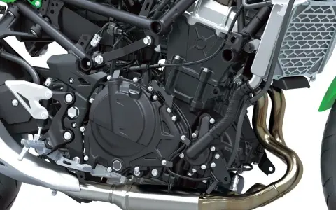 Dettaglio motore di una moto, con tubi di scarico lucidi e componenti meccanici complessi. Il freno motore è parte integrante di questo sistema.