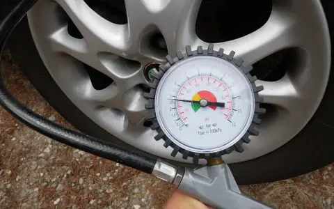 Misurazione della pressione delle gomme auto con manometro. La lancetta indica circa 2.5 bar.