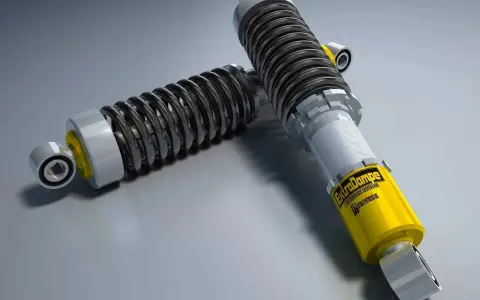 Due ammortizzatori auto di alta qualità, uno giallo con logo "ExtraDampe", pronti a migliorare le prestazioni su strada.